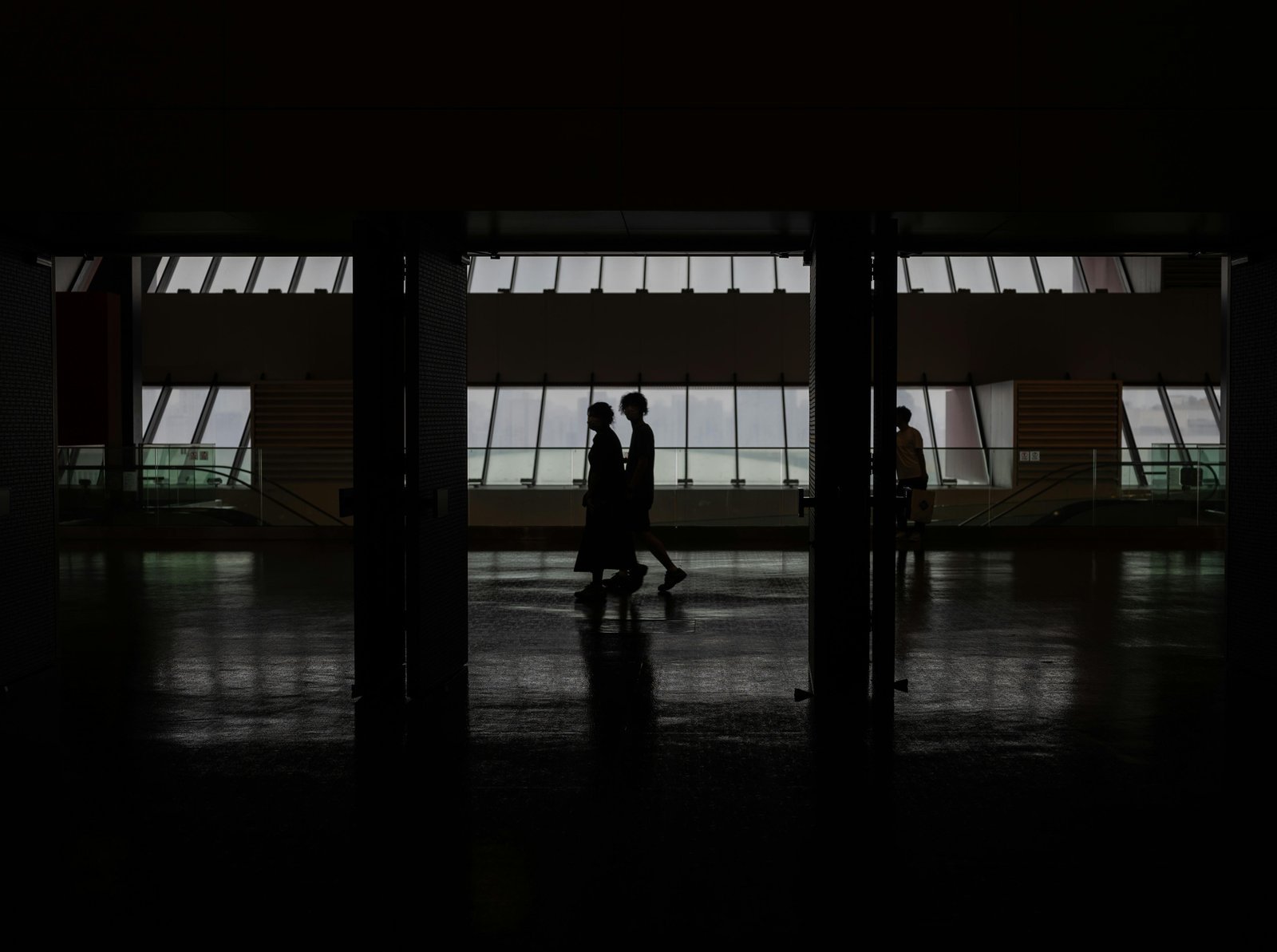 Silhouette of people walking through a modern hallway with large windows in Shanghai, China.